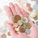 Close-up of a hand holding diverse coins, symbolizing global currency and finance.