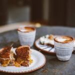 Grilled cheese sandwich and artisan coffee on a rustic table setting, perfect morning meal.